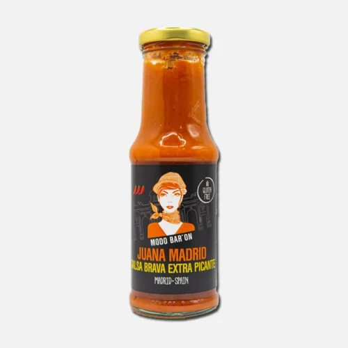 Salsa picante en botella de vidrio, con etiqueta colorida que incluye ilustración de una mujer cocinera y texto en español. Ideal para realzar el sabor de platos mexicanos.